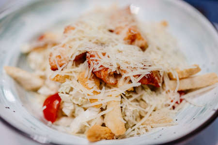 Caesar salad with chicken in a white bowl.