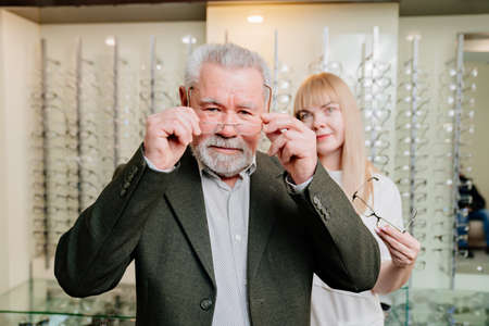 an elderly man with an ophthalmologist chooses glasses in the optics salon.