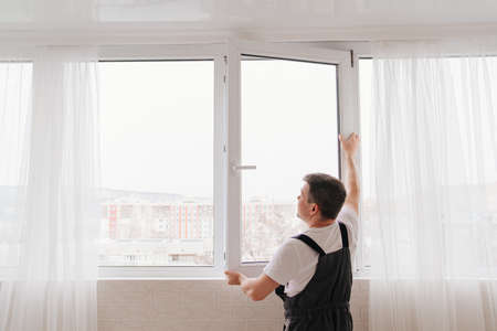 a repairman repairs, adjusts or installs metal-plastic windows in the apartment.