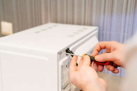 a man repairs a microwave. handyman services.