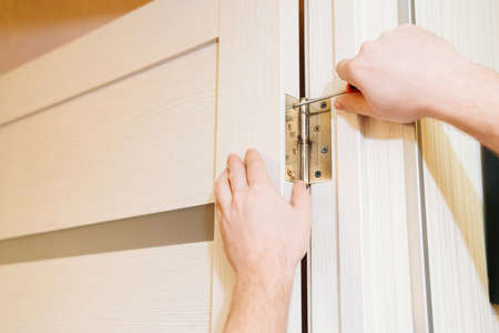 a repairman repairs the door. installation and adjustment of fasteners