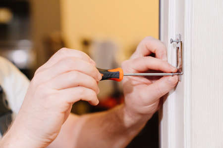 a repairman repairs the door. handyman service.の写真素材