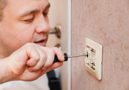 a man repairs an electrical outlet. electrician and handyman services.