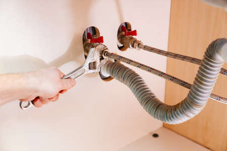 A male plumber with wrench repairs the water pipes in the bathroom.の写真素材
