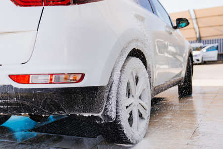 white car in foam. self-service car wash. car washer.