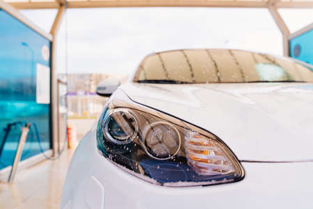 water droplets on the headlight of a white car. self-service car wash. car washer.の写真素材