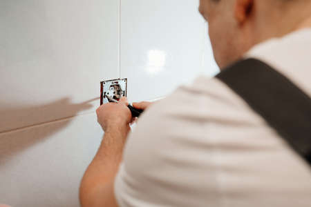 a man repairs an electrical outlet. electrician and handyman services.の写真素材