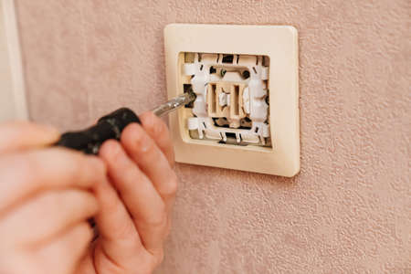 a man repairs an electrical outlet. electrician and handyman services.