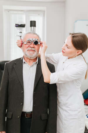 ophthalmologist makes selection of lenses, diagnoses a elderly mans vision.の写真素材