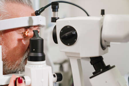 examination of elderly man with slit lamp. medical equipment