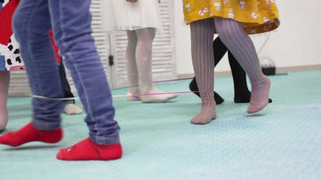 childrens legs walk in circles in a game with a rope.