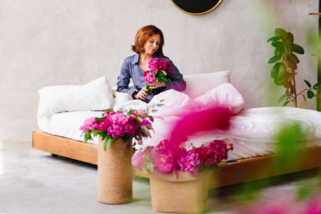happy morning. a woman in pajamas in bed with a peonies.の写真素材