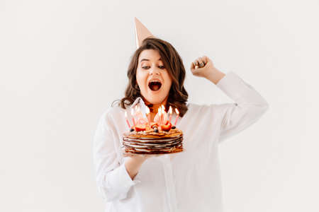 a funny woman with a birthday cake with candles.の写真素材