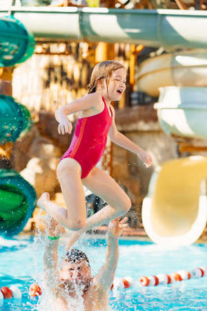 dad throws up his daughter, they have fun and play together in the pool.の写真素材