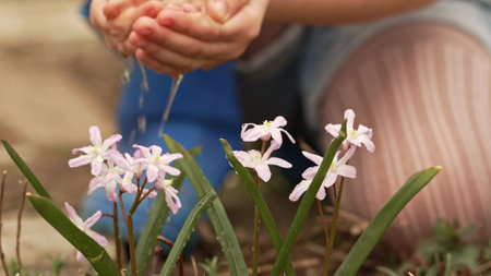 a little girl watering flowers from the palms of her hands.の写真素材