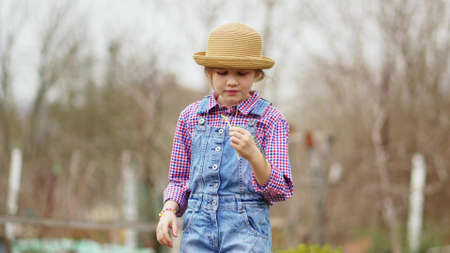 a funny little girl in a hat eats green onions and waves at the sharpnessの写真素材