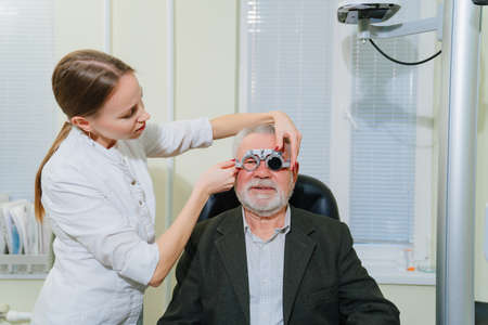 ophthalmologist makes selection of lenses, diagnoses a elderly mans vision.の写真素材