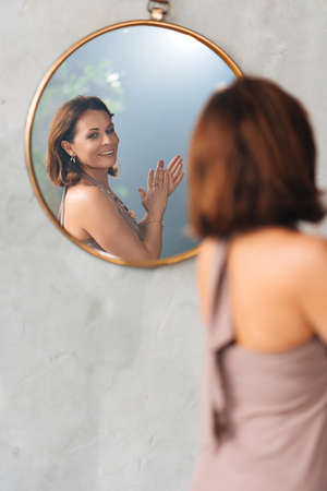 an attractive woman admires her reflection in a round mirror.の写真素材