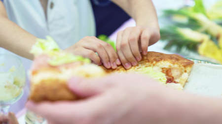 childrens hands tear off a slice of pizza. traditional treat for a children.の写真素材