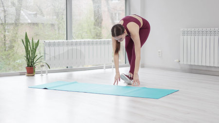 warm-up and stretching. a woman in a burgundy tracksuit exercises in a gym.