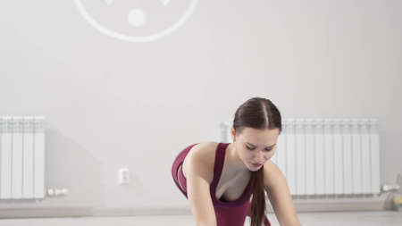 a woman in a tracksuit does leg exercises with gymnastic elastic bands on a mat
