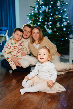 a happy family with two small children at home by the Christmas tree.の写真素材