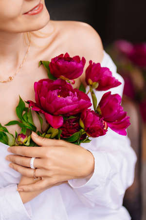 tenderness. a blonde woman in a white shirt and a bouquet of peonies.の写真素材