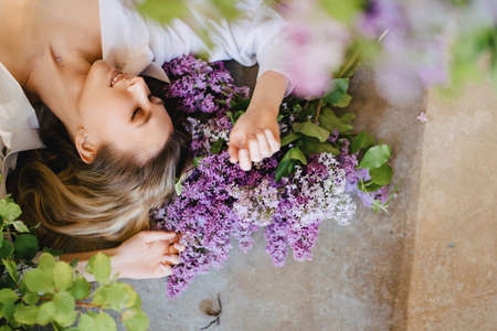 view top. a blonde in a white shirt on the floor with lilac flowers.の写真素材