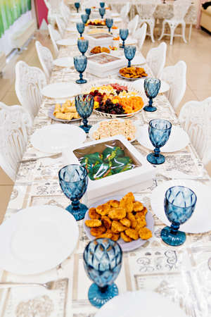 a large festive table with appetizers and glasses of blue glass.