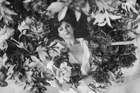a beautiful and gentle young woman lies in peony flowers. feminine beauty.の写真素材