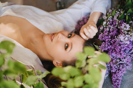 a sexy topless blonde in a white shirt on the floor with lilac flowersの写真素材