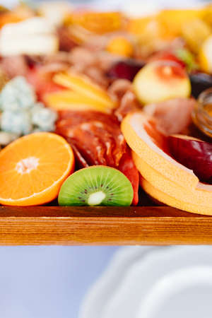 assorted fruits, berries, cheese, sausage, snacks and honey on a tray.の写真素材