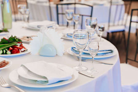empty wine glasses on a round table with a white tablecloth.の写真素材