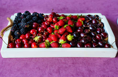 tray with strawberries, cherries and blackberries on a tray.の写真素材