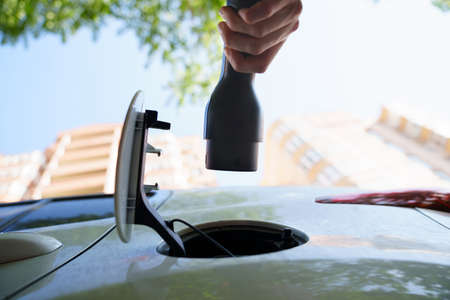hand of woman plugging in an electric car at outlet socket.の写真素材