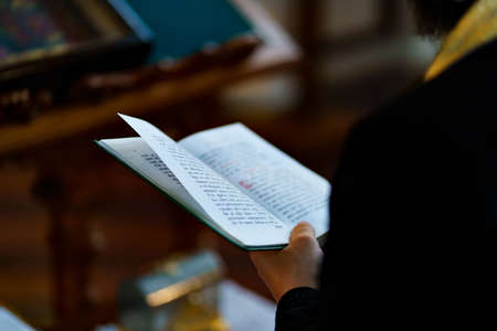 the hands of a priest with a prayer book at a religious service in the church.
