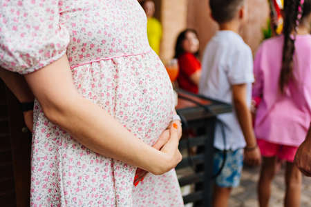 a pregnant woman in a summer dress strokes her stomach.の写真素材