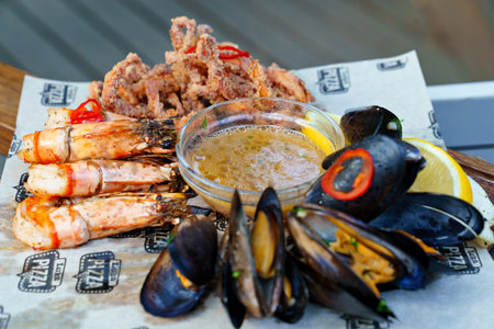 seafood. mussel, squid and shrimp cooked on the grill with sauce and vegetables.のeditorial素材