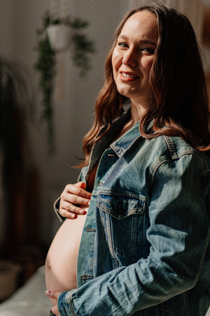 a beautiful pregnant woman in a denim jacket with a naked tummyの写真素材