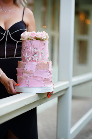 woman with two-tier pink cake with rosebuds and the inscription happy birthday.の写真素材