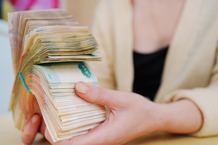 womens hands hold a stack of rubles tied with a rubber band.