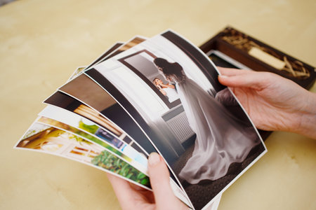 printed wedding photos in the hands and in a wooden box with a flash drive.