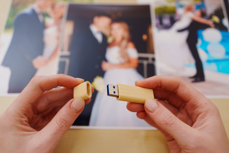 selective focus. printed wedding photos, wooden box and hands with flash driveの写真素材