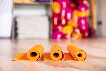 orange rolled up yoga and gymnastics mats on the floor.の写真素材