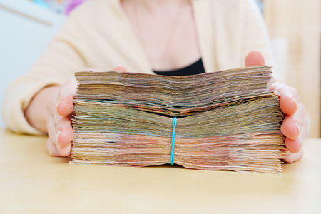 womens hands hold a stack of rubles tied with a rubber band.