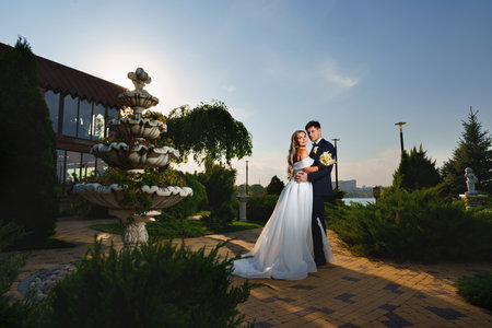 groom and bride in traditional wedding clothes cuddling in park. sunsetの写真素材