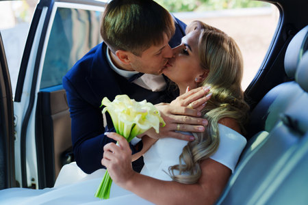 the bride and groom kiss in the back seat of the car. happy newlyweds.の写真素材
