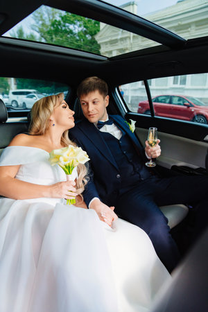 the bride and groom in the back seat of the car. happy newlyweds.の写真素材