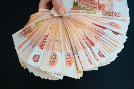 a woman holds in hands a fan of banknotes of 5000 rubles on a black background.の写真素材