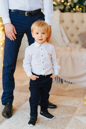 a cute little boy in black pants and a white shirt next to daddy.の写真素材